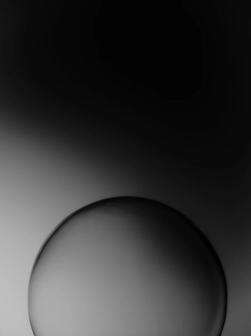 partial silhouette of the top of a sphere emerging from a dark gradient background