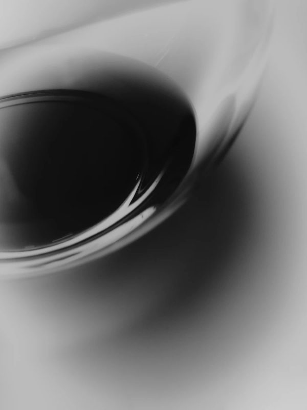 dettaglio macro in bianco e nero di una superficie curva in cristallo che incontra un liquido scuro