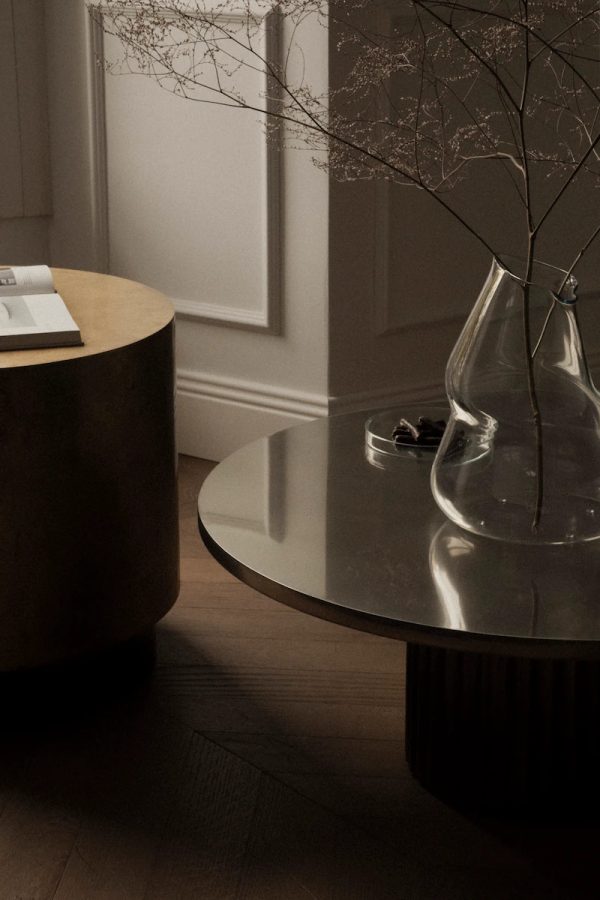 primo piano di tavolini decorativi in ottone e acciaio con un vaso contemporaneo di vetro trasparente