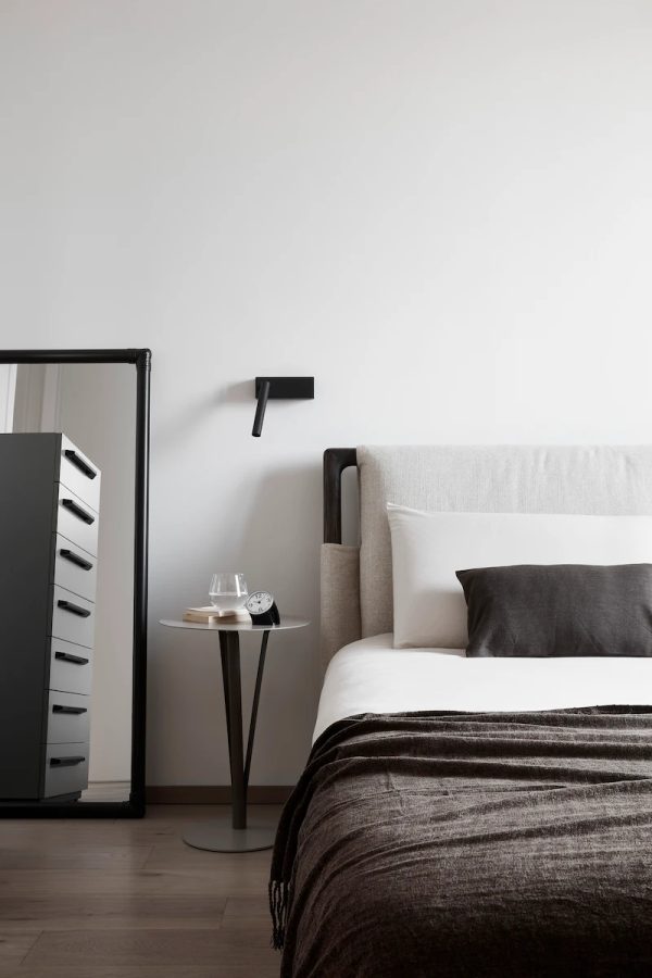 camera da letto moderna con letto imbottito, comodino essenziale e grande specchio appoggiato alla parete