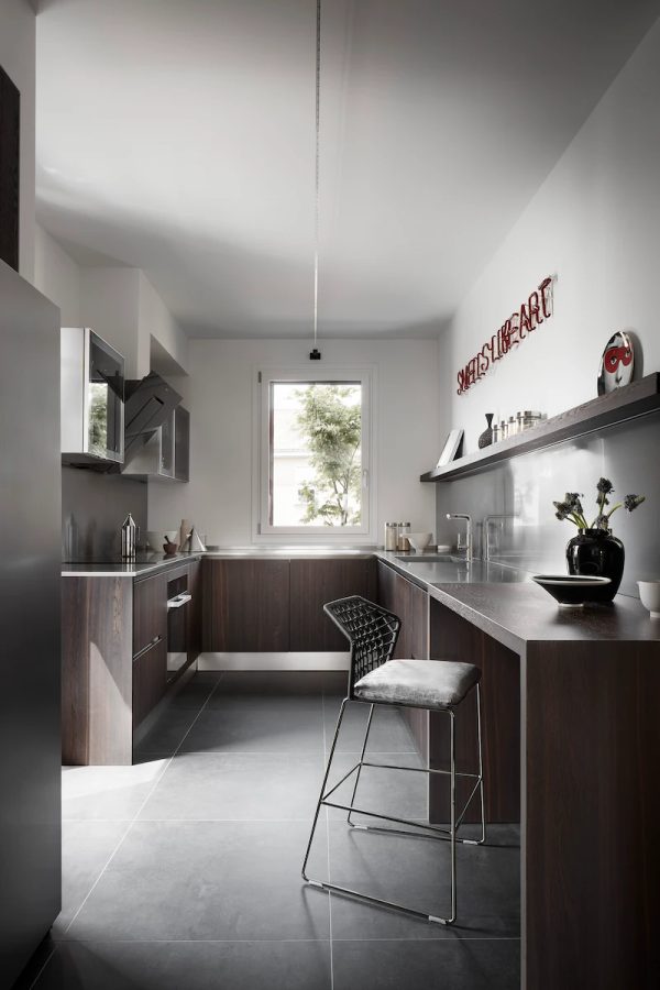 cucina di design con mobili in legno, dettagli in acciaio e illuminazione elegante, completata da un grande sgabello moderno