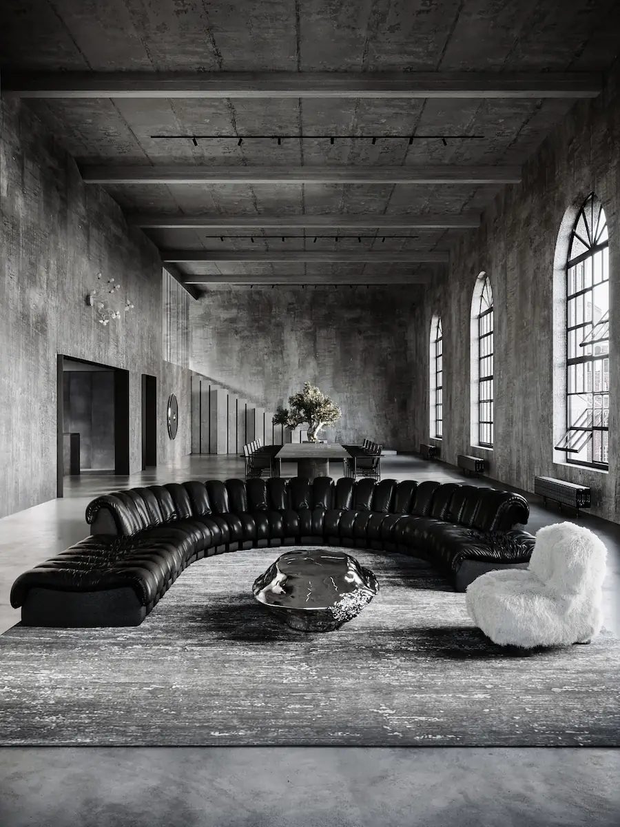 spacious industrial concrete loft with a semicircular leather sofa, sculptural metal table, and white fur armchair