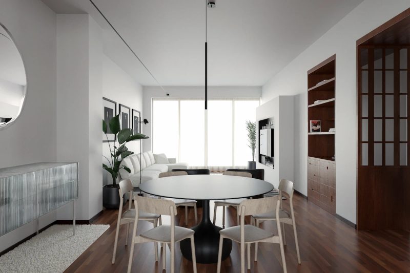 dining room with round black table and light wood chairs, reflections on a round mirror and vintage glass sideboard