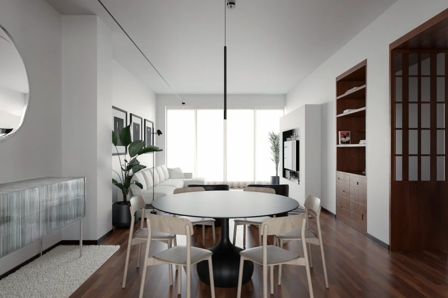 sala da pranzo con tavolo tondo nero e sedie in legno chiaro, riflessi su specchio tondo e credenza in vetro vintage