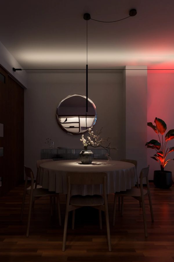 sala da pranzo illuminata con luce d’accento, tavolo tondo decorato con vaso di fiori sotto lampada a sospensione