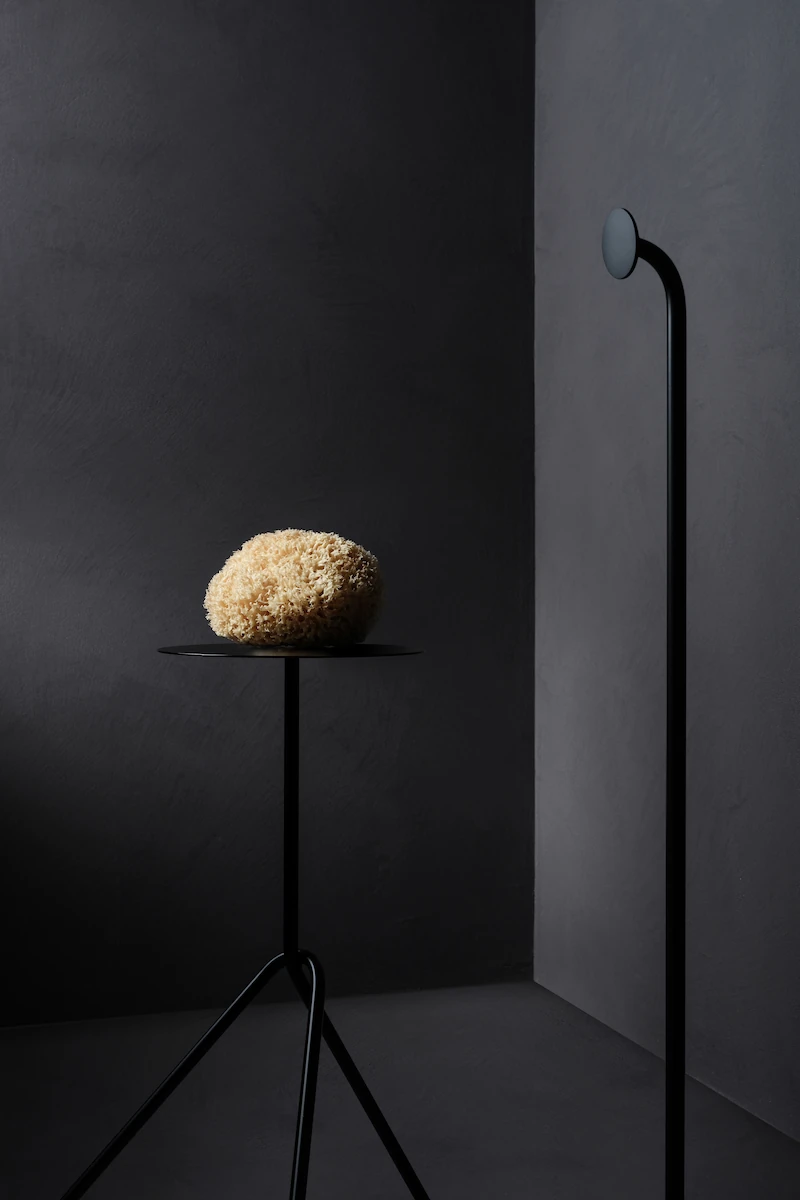 spugna naturale su tavolino nero minimal in metallo, in un ambiente moderno con pareti grigie