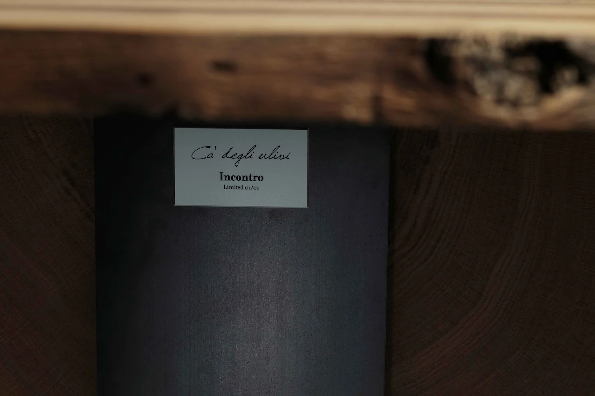 lavabo cilindrico freestanding in acciaio nero con rubinetto e manopola a muro, inserito in un contesto di design minimal