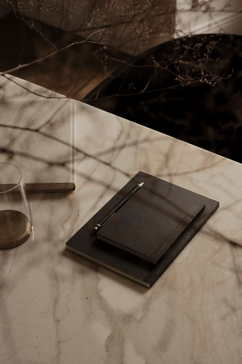 dettaglio di quaderno giapponese e bicchiere su tavolo in marmo, oggetti da ufficio e pianta decorativa