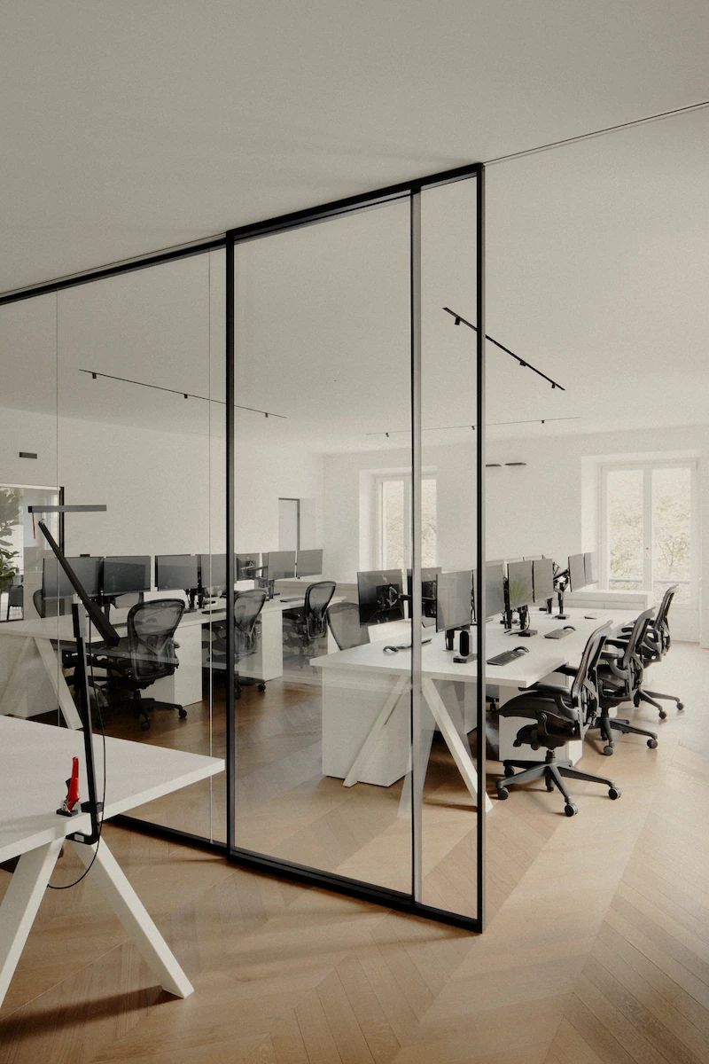 ufficio moderno con postazioni in vetro e sedie nere, atmosfera luminosa e funzionale