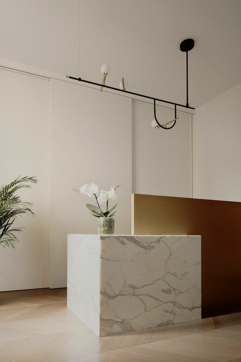 reception moderna con bancone in marmo bianco e ottone, lampada a sospensione minimalista
