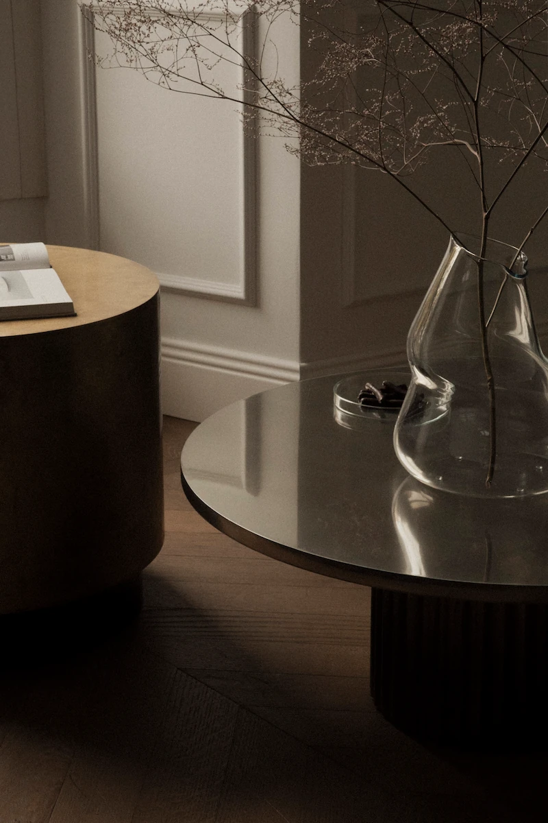 primo piano di tavolini decorativi in ottone e acciaio con un vaso contemporaneo di vetro trasparente