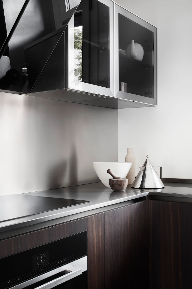 angolo cucina con piano di lavoro in acciaio spazzolato e mobili in legno scuro, decorata con accessori eleganti e moderni