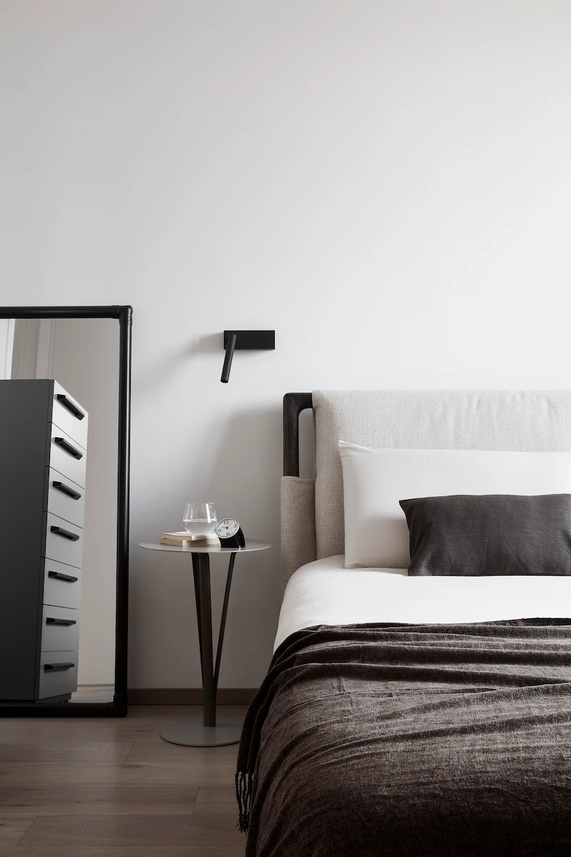 camera da letto moderna con letto imbottito, comodino essenziale e grande specchio appoggiato alla parete