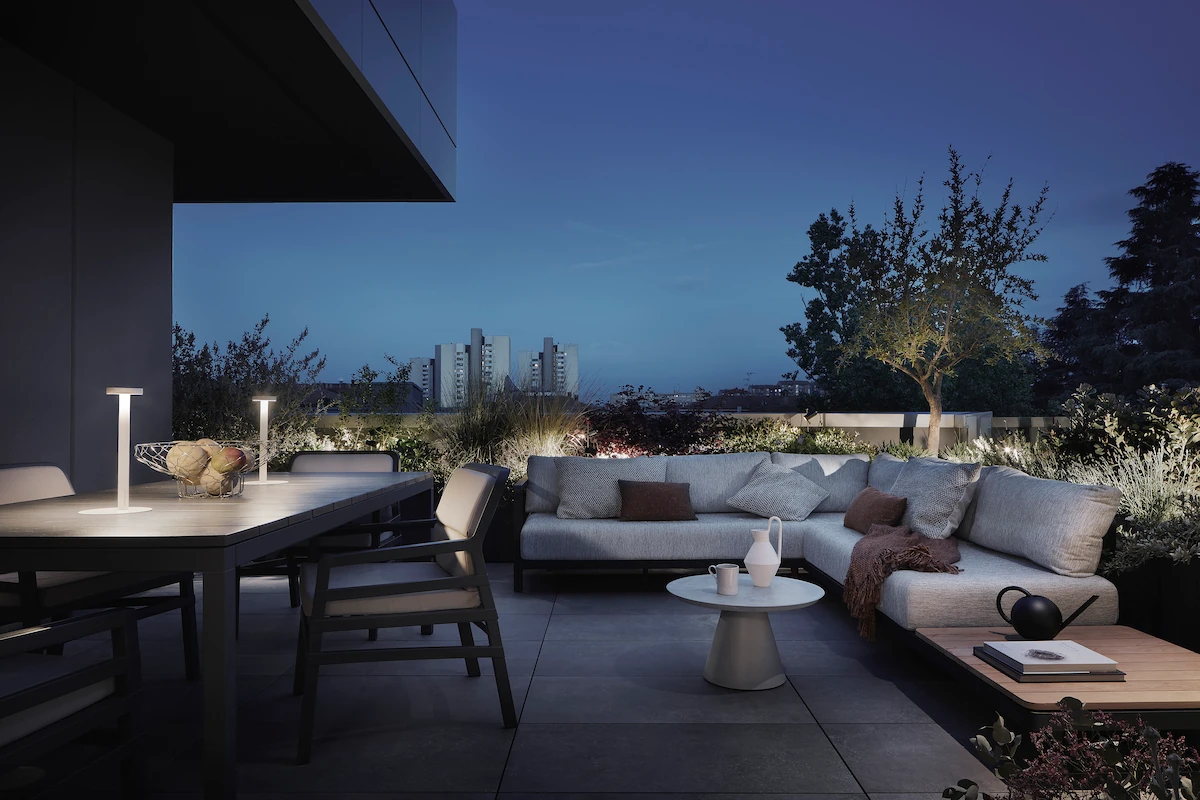 terrazza moderna arredata con tavolo da pranzo e area salotto, illuminata delicatamente al tramonto