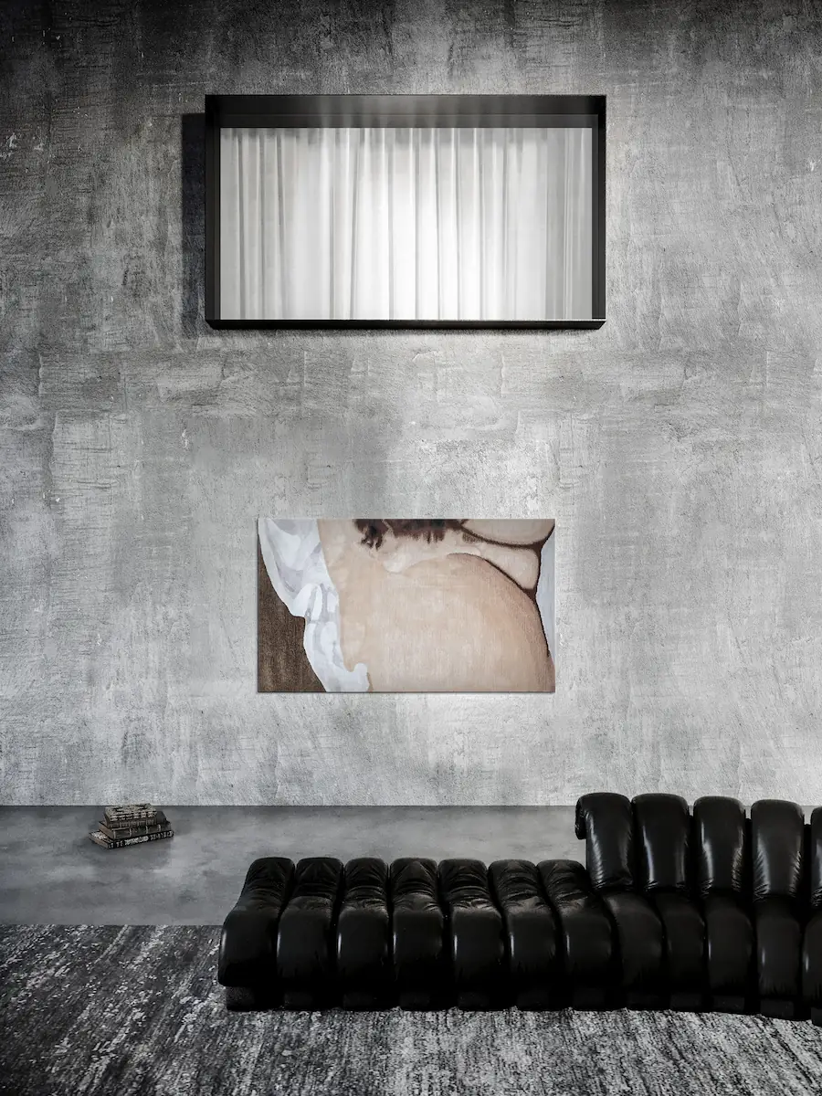 divano modulare nero, pareti in cemento e opera d’arte moderna in tessuto sotto un’ampia finestra con telaio moderno