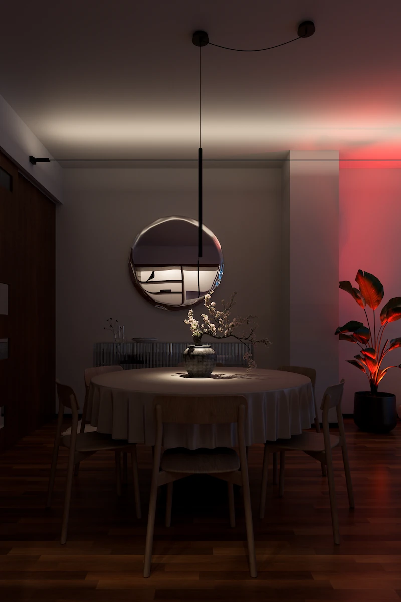 sala da pranzo illuminata con luce d’accento, tavolo tondo decorato con vaso di fiori sotto lampada a sospensione
